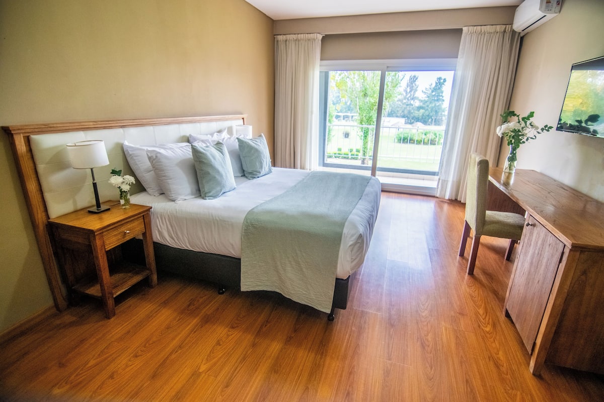 A hotel room with a bed, a nightstand, a desk, and a chair.