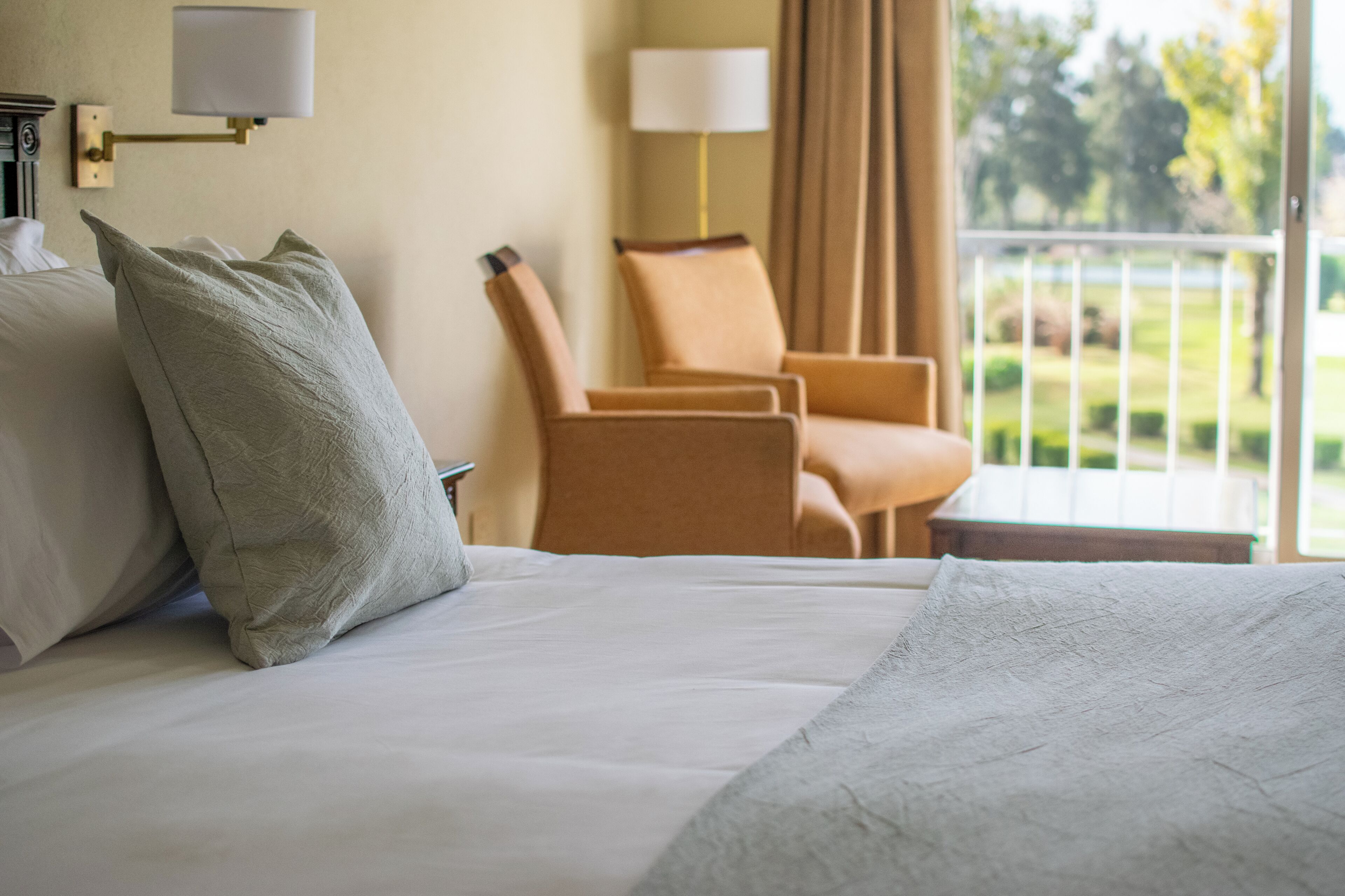Una habitación de hotel con cama, una silla y vistas al exterior.