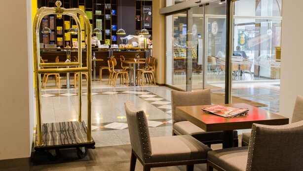 A hotel lobby with a seating area, a reception desk, and a large window offering a view of the street. - San Nicolas Plaza Hotel (San Nicolas de los Arroyos)