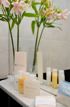 A bathroom counter with toiletries and a vase of flowers. - San Nicolas Plaza Hotel (San Nicolas de los Arroyos)