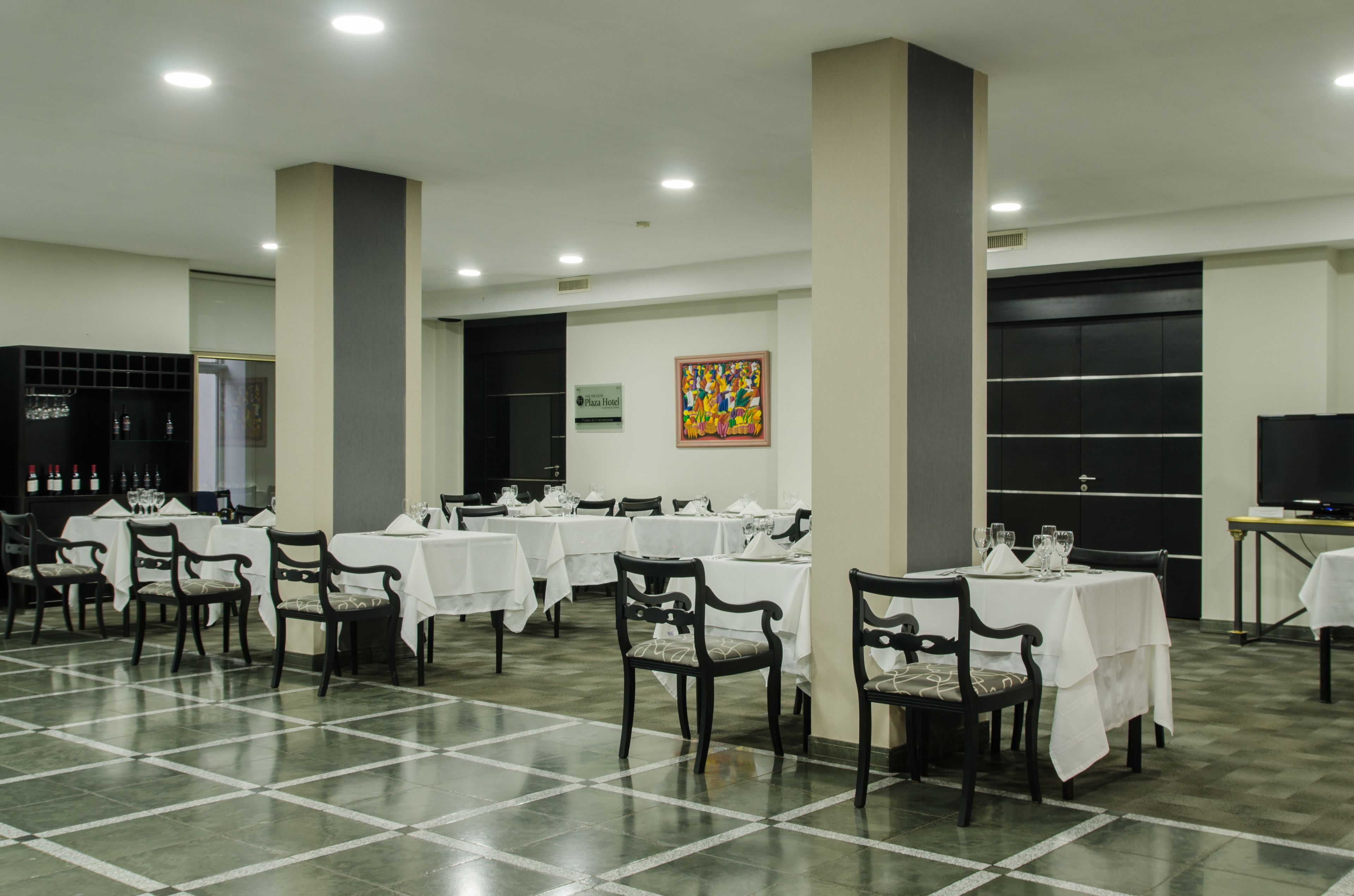 A spacious dining area with multiple tables and chairs, a large pillar, and a sign indicating a Pizza Hotel.