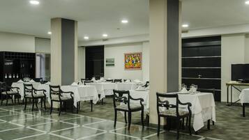 A spacious dining area with multiple tables and chairs, a large pillar, and a sign indicating a Pizza Hotel.