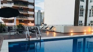 A rooftop pool with lounge chairs and a sun umbrella. - San Nicolas Plaza Hotel (San Nicolas de los Arroyos)