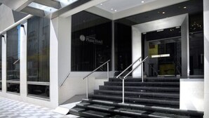 A modern building with a checkered floor pattern, a staircase leading to a dark entrance, and a sign reading "Plaza Hotel". - San Nicolas Plaza Hotel (San Nicolas de los Arroyos)