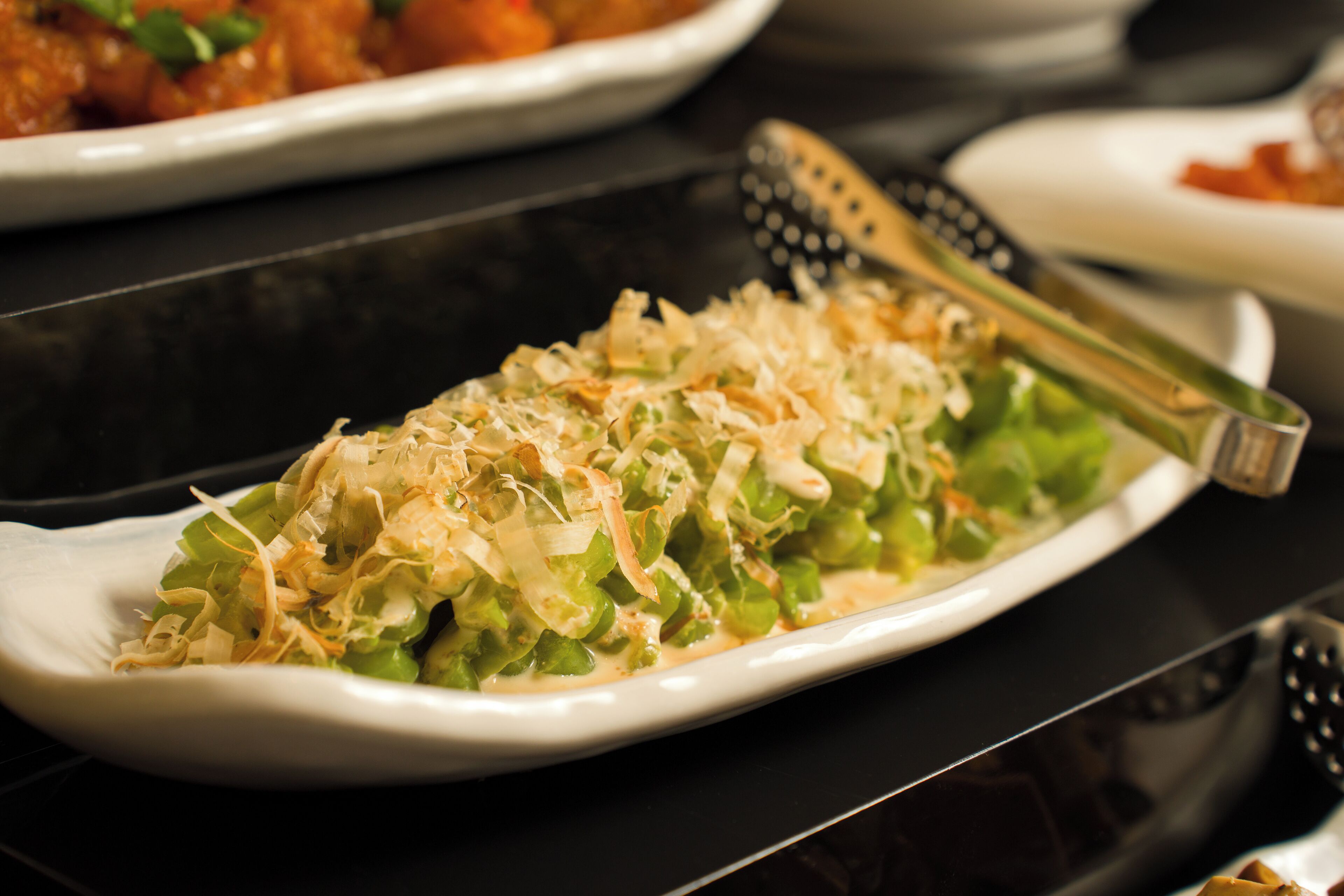 A plate of food with shredded toppings, a knife, and a bowl in the background.