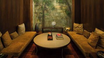 A cozy room with a round table, two sofas, a globe, and a decorative wall with a tropical mural.