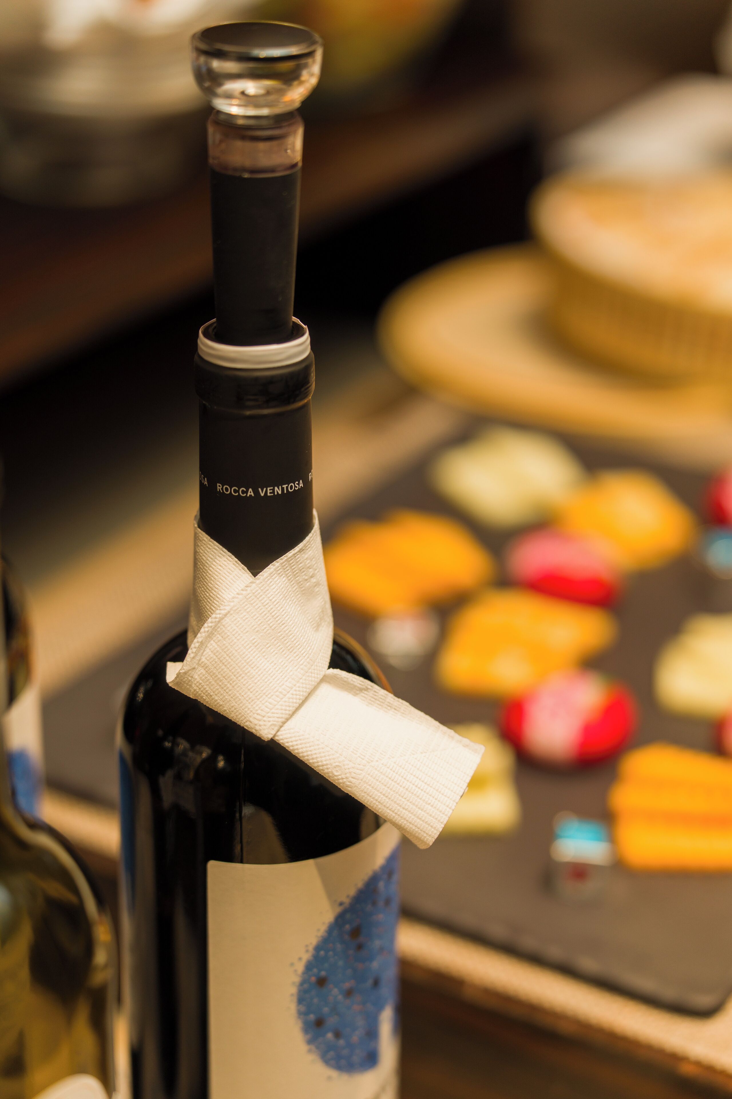 A bottle of wine with a label and a white ribbon tied around the neck.