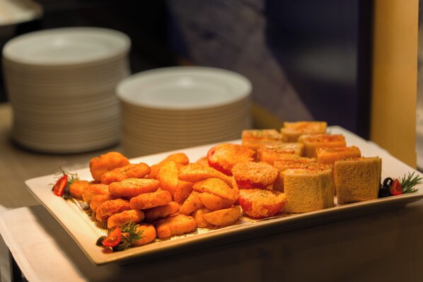 Une table de buffet proposant une variété de plats, notamment du pain et des légumes rôtis.