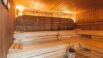 A sauna with wooden benches and a bucket of towels.