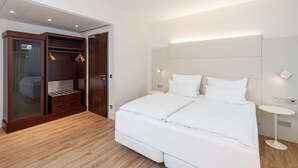 A modern bedroom with a large bed, a wardrobe with glass doors, and a bedside table.