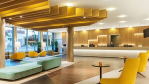 A modern lobby with a reception desk, seating areas, and large windows.