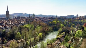 Ein Fluss fließt durch eine Stadt mit historischen Gebäuden und einem markanten Kirchturm.