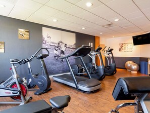 Un gimnasio con bicicletas estáticas, cintas de correr y pelotas de ejercicio.