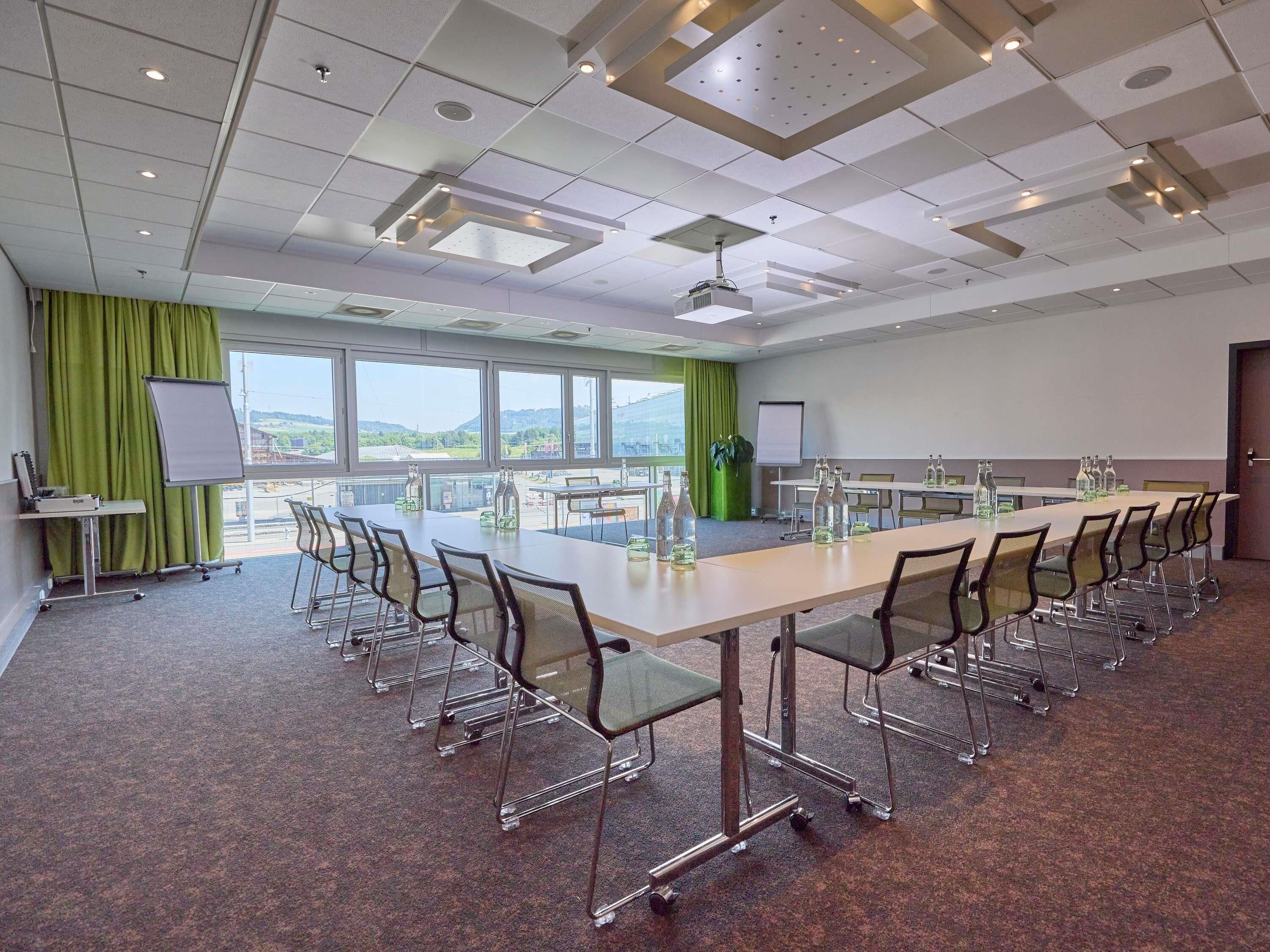 A conference room with a long table, chairs, a projector, and a whiteboard.
