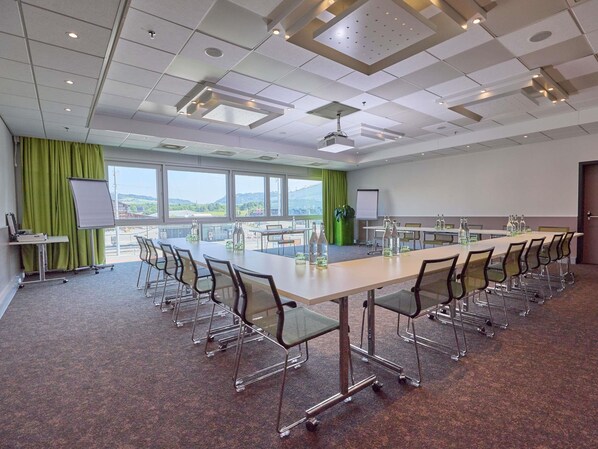 A conference room with a long table, chairs, a projector, and a whiteboard.