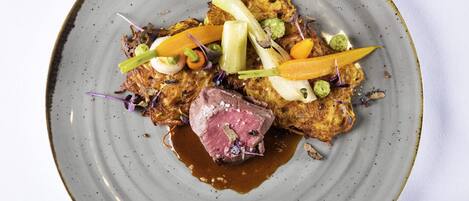 Un plato de comida con un bistec, verduras y salsa.