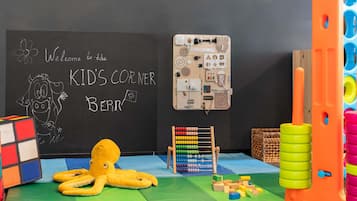 Ein Kinderspielbereich mit einer Schiefertafel, einem Oktopus-Spielzeug, Bauklötzen und einer hölzernen Spielanlage.