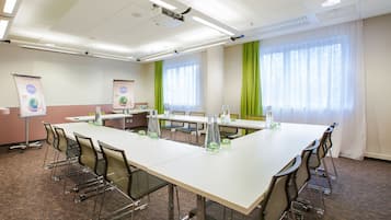 A conference room with a long table, chairs, a projector, and presentation screens.