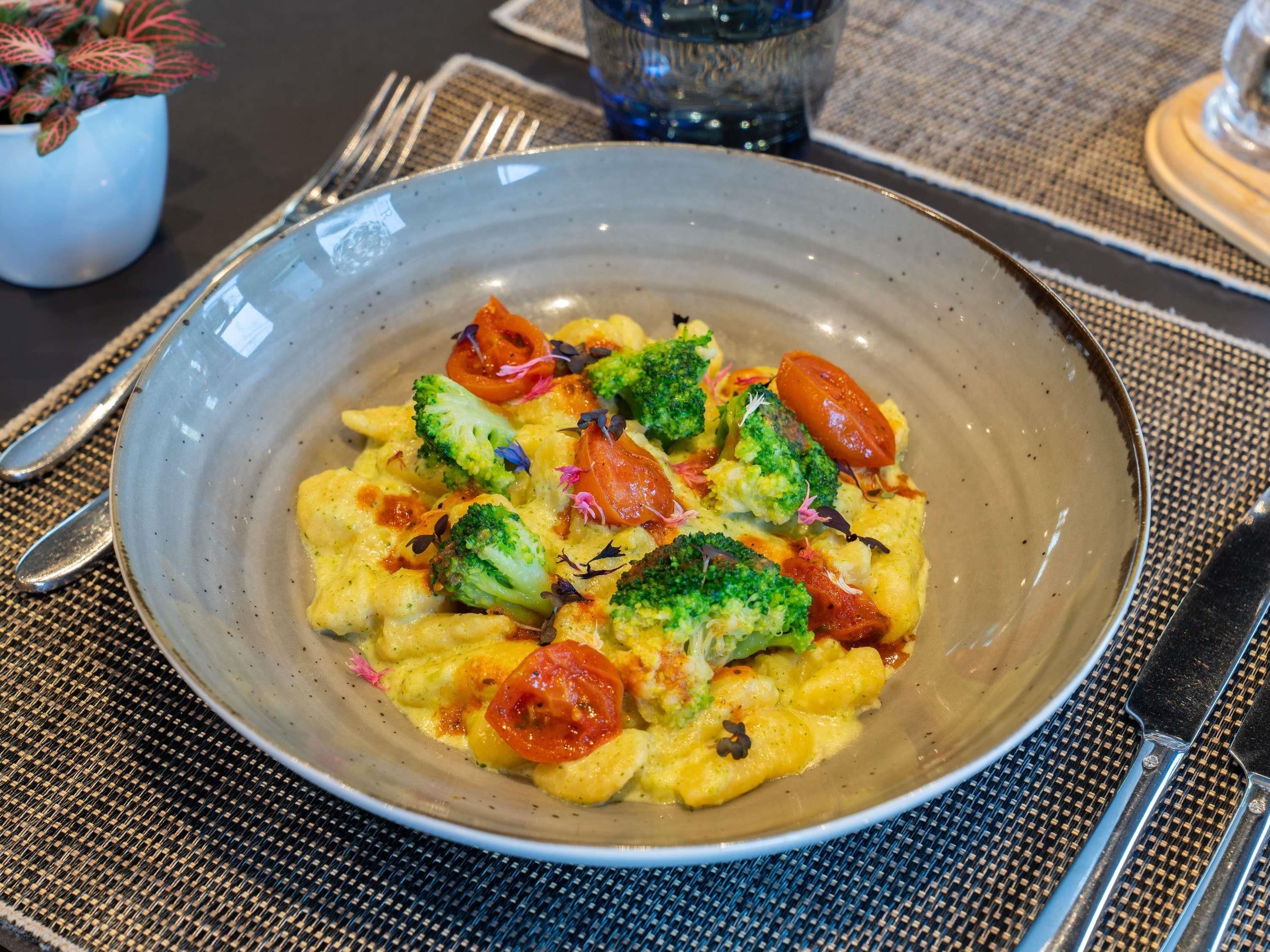 A plate of food with broccoli and tomatoes on a textured placemat.