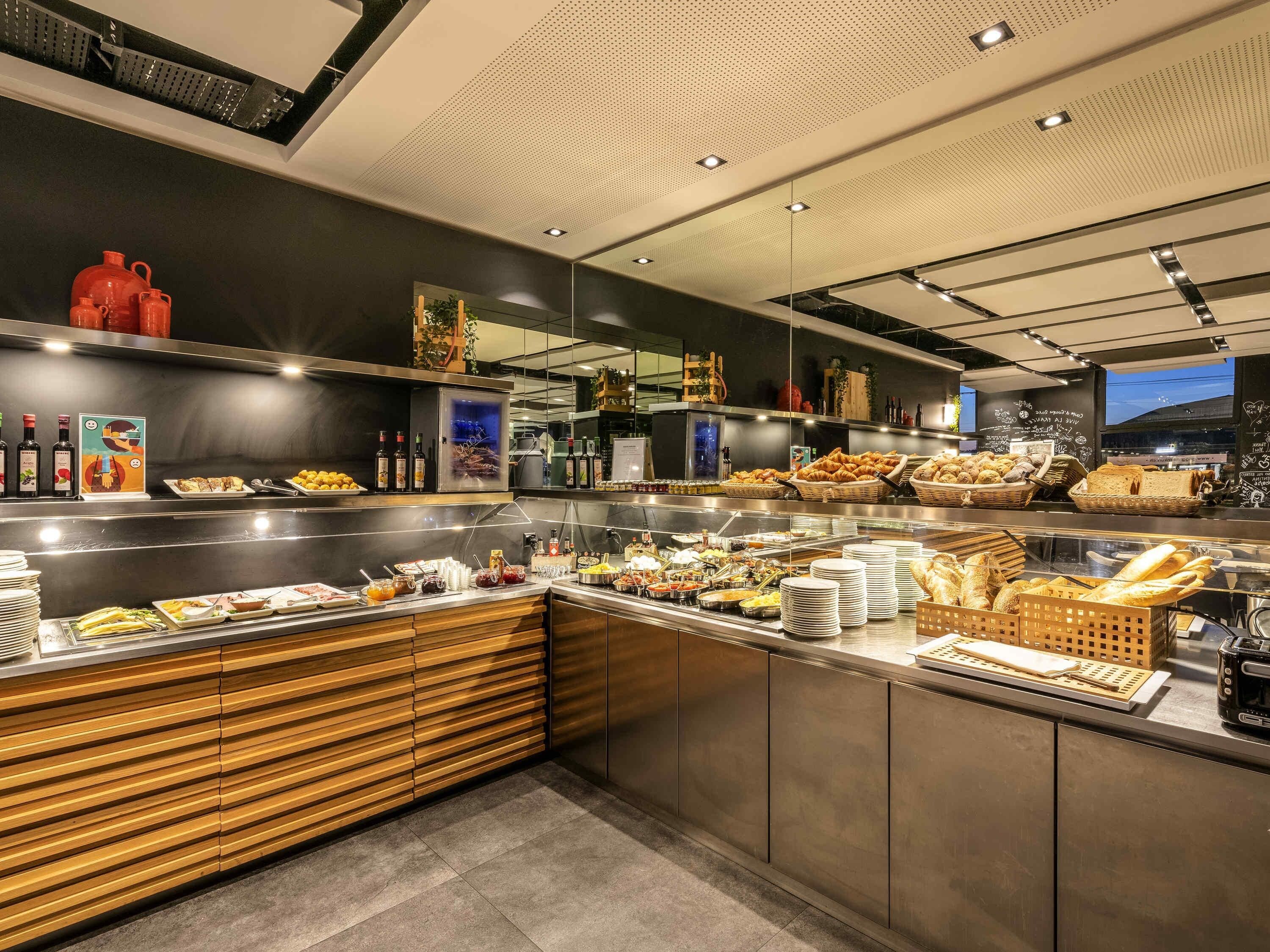 Ein reichhaltiges Buffet mit verschiedenen Speisen und Getränken, eine Holztresen und ein modernes Deckenkonzept.