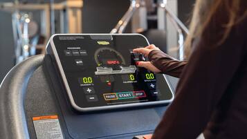 Una bicicleta estática con pantalla digital, panel de control y una etiqueta con instrucciones de seguridad.