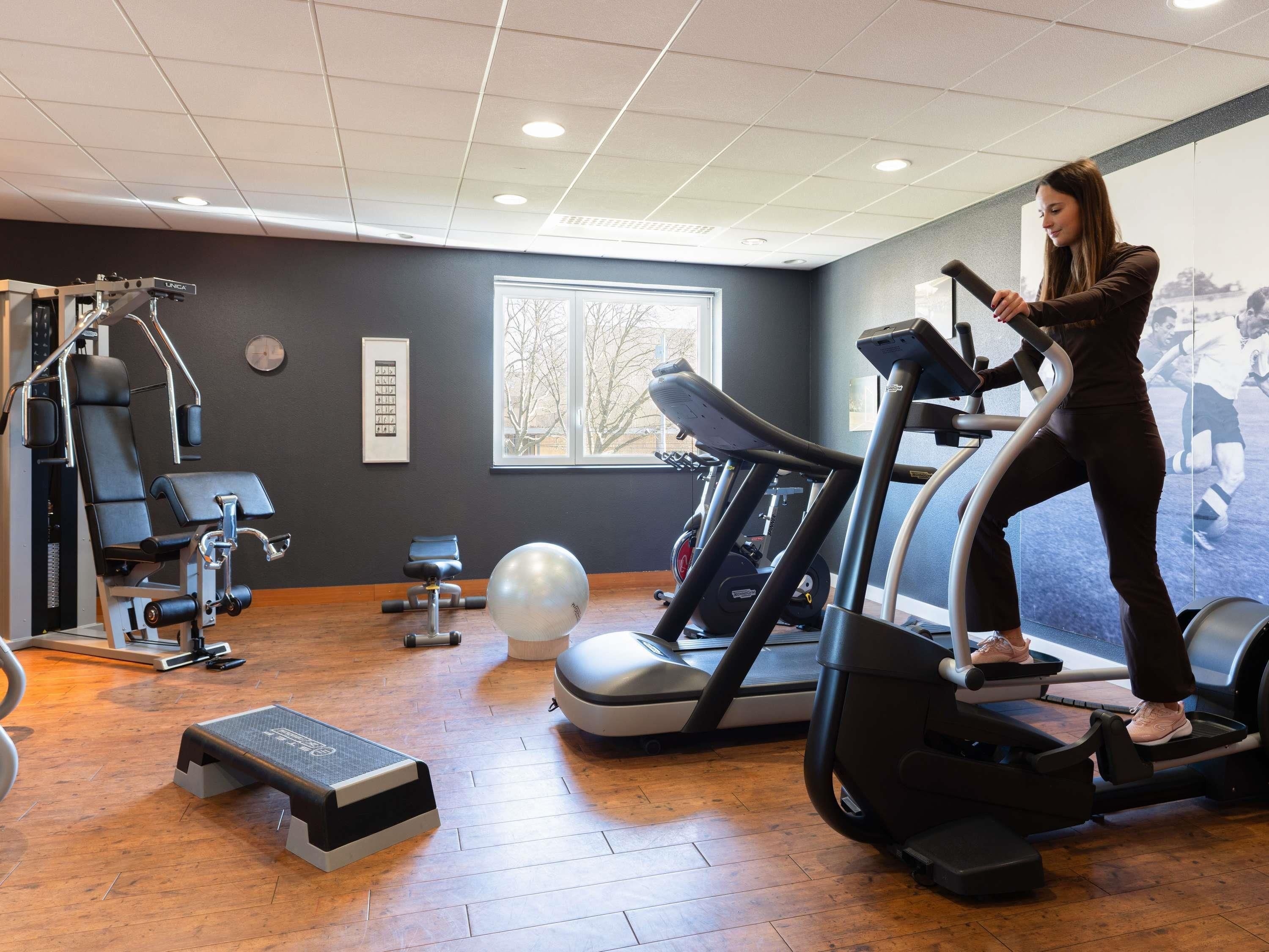 A gym with exercise equipment, a step platform, and a large window.