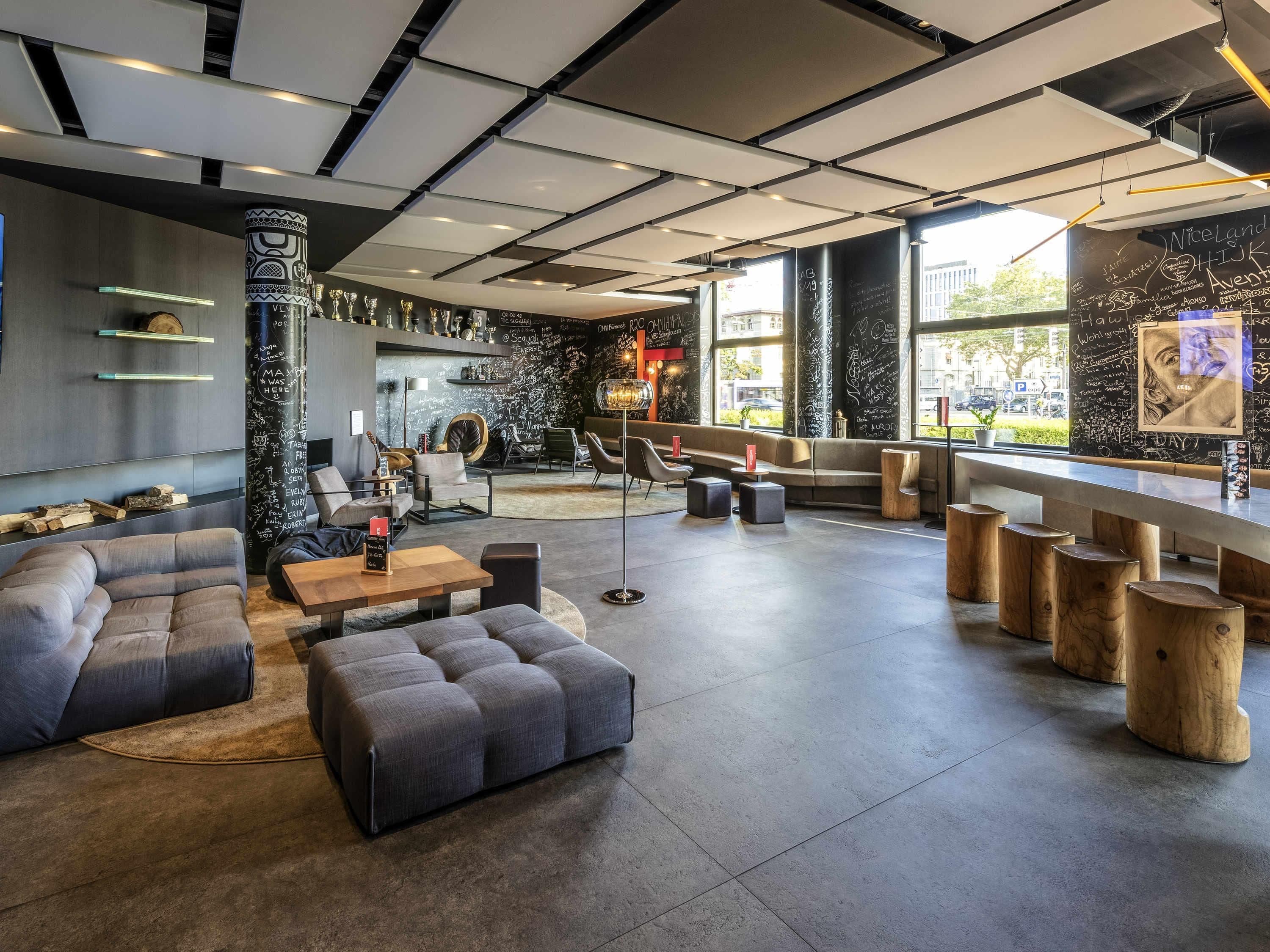 Un área de lounge moderna con asientos, una barra de café y una pared de pizarra con anotaciones.
