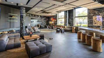 Un espace de détente moderne, doté de sièges, d’un bar à café et d’un mur noir où sont écrits divers messages.
