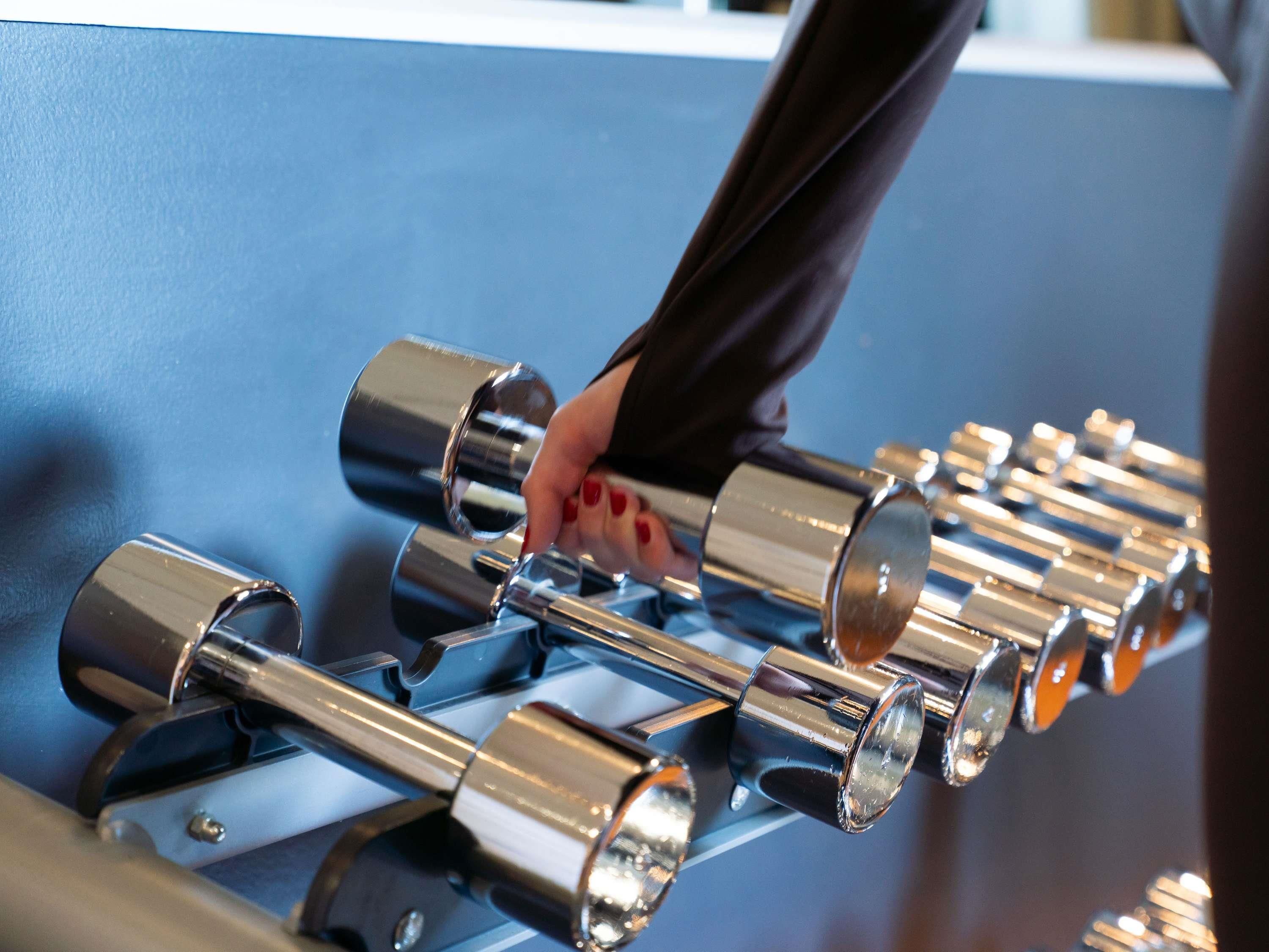 A hand adjusting a series of metallic cylindrical objects, likely part of a mechanical or industrial setup.