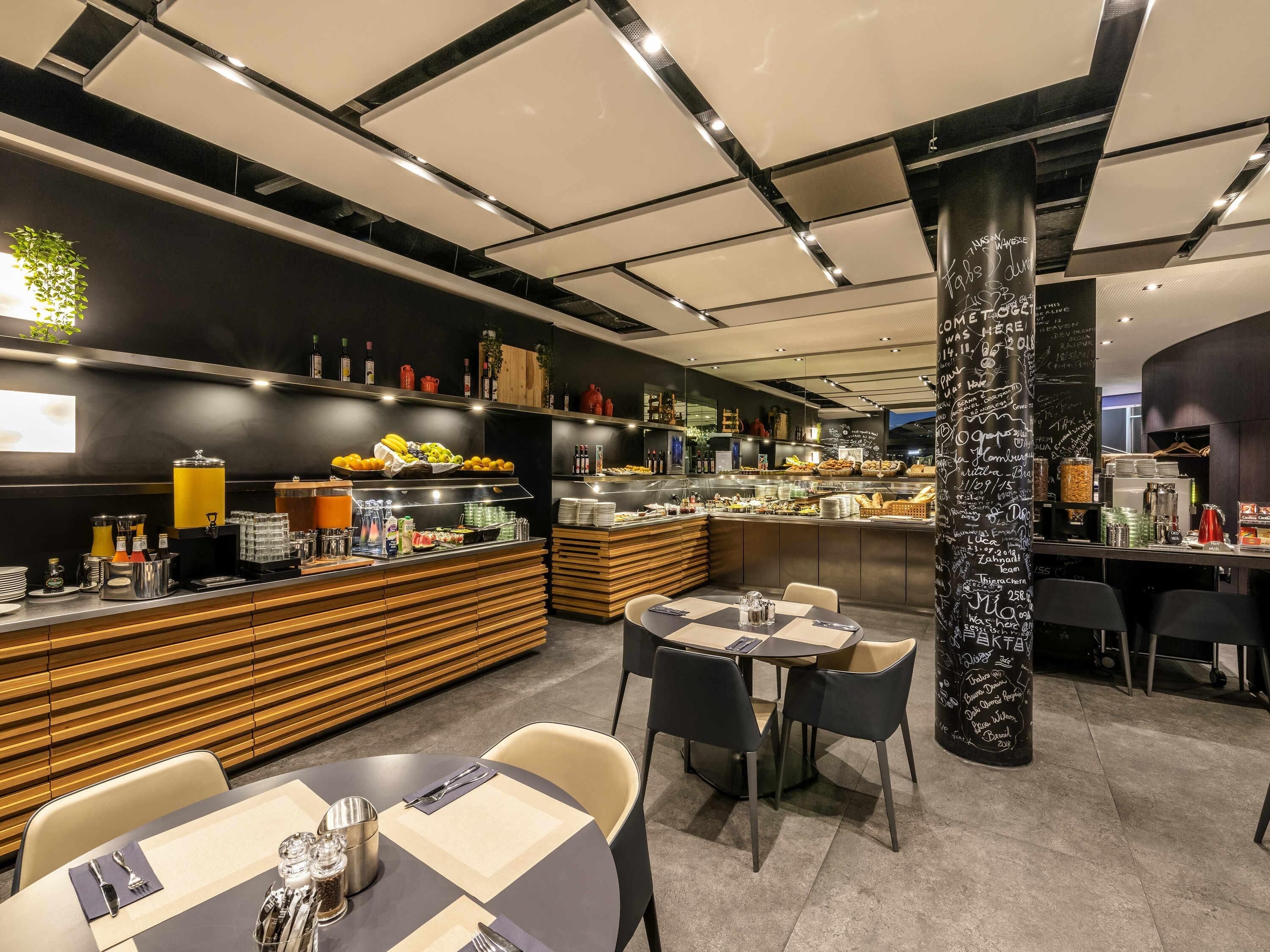 Ein modernes Restaurant-Interieur mit Buffet, Sitzbereich und einer Tafelwand mit Schrift.