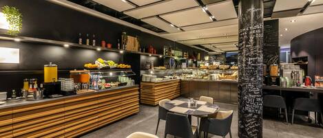 Ein modernes Restaurant-Interieur mit Buffet, Sitzbereich und einer Tafelwand mit Schrift.