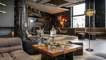 Ein moderner Loungebereich mit einem Holztisch, Sitzgelegenheiten und einer großen, verzierten Säule mit Inschriften.