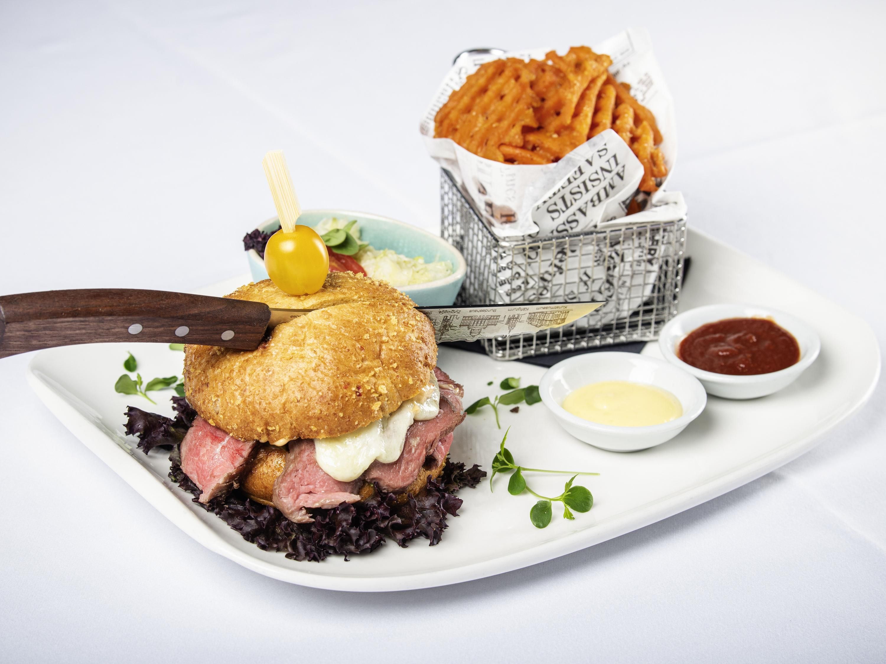 A plate with a sandwich, fries, and two dipping sauces.