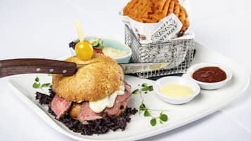 Un plato con un sándwich, papas fritas y dos salsas para mojar.