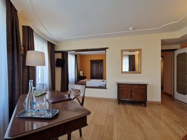 Una habitación de hotel con un escritorio de madera, una cama, un aparador y un televisor.