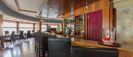 A bar area with wooden paneling, bar stools, and a glass display case with bottles.