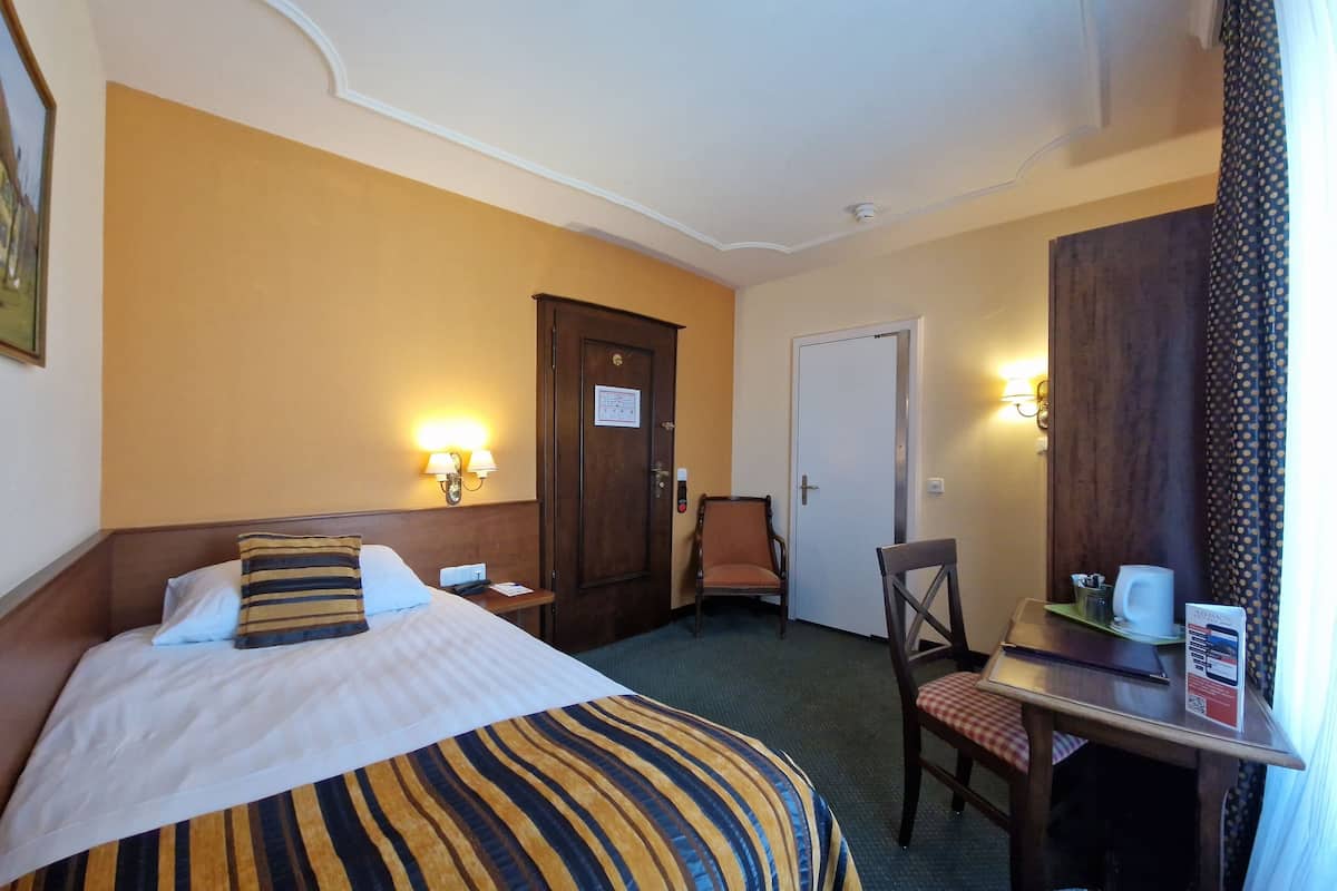 Una habitación de hotel con cama, escritorio, silla y puerta.