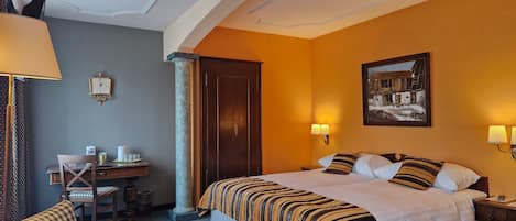 Una habitación de hotel con cama, escritorio, silla y un cuadro en la pared.