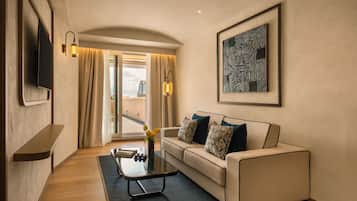 A modern living room with a sofa, a coffee table, a flat-screen TV, and a painting on the wall.