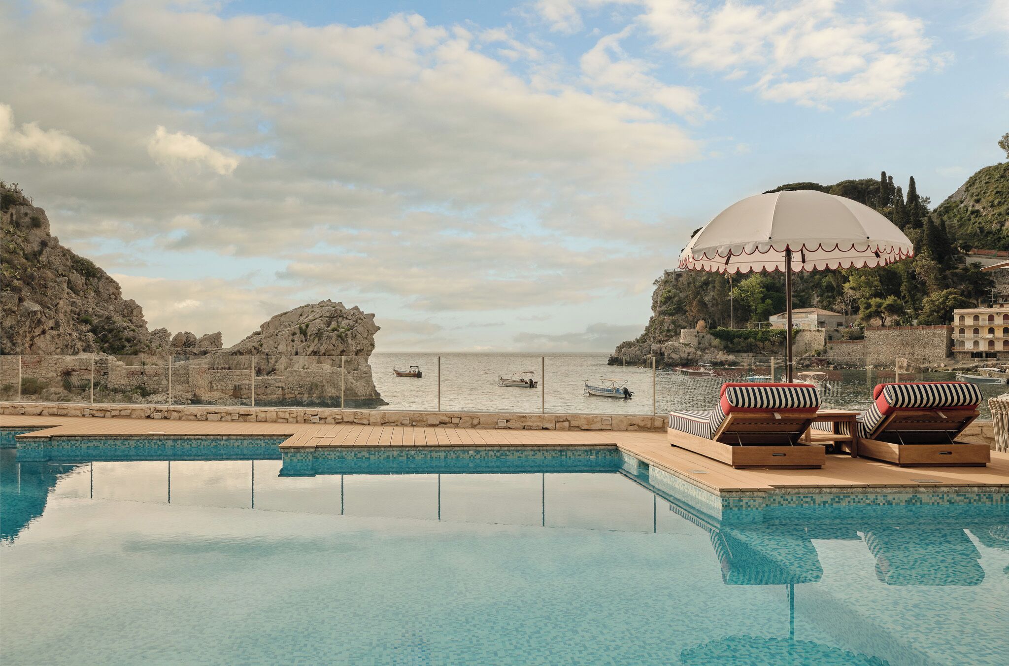 Una piscina al aire libre, sombrillas, sillones reclinables de piscina