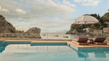 Una piscina al aire libre, sombrillas, sillones reclinables de piscina