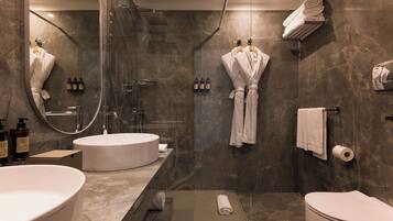 Ein modernes Badezimmer mit einer Duschkabine, zwei Waschbecken, einer Toilette und einem Handtuchhalter.