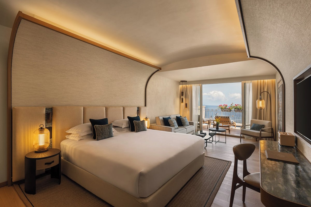 Une chambre d’hôtel moderne avec un grand lit, un bureau et une vue sur l’océan.