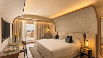 A modern hotel room with a large bed, a desk with a chair, a TV, and a window with curtains.