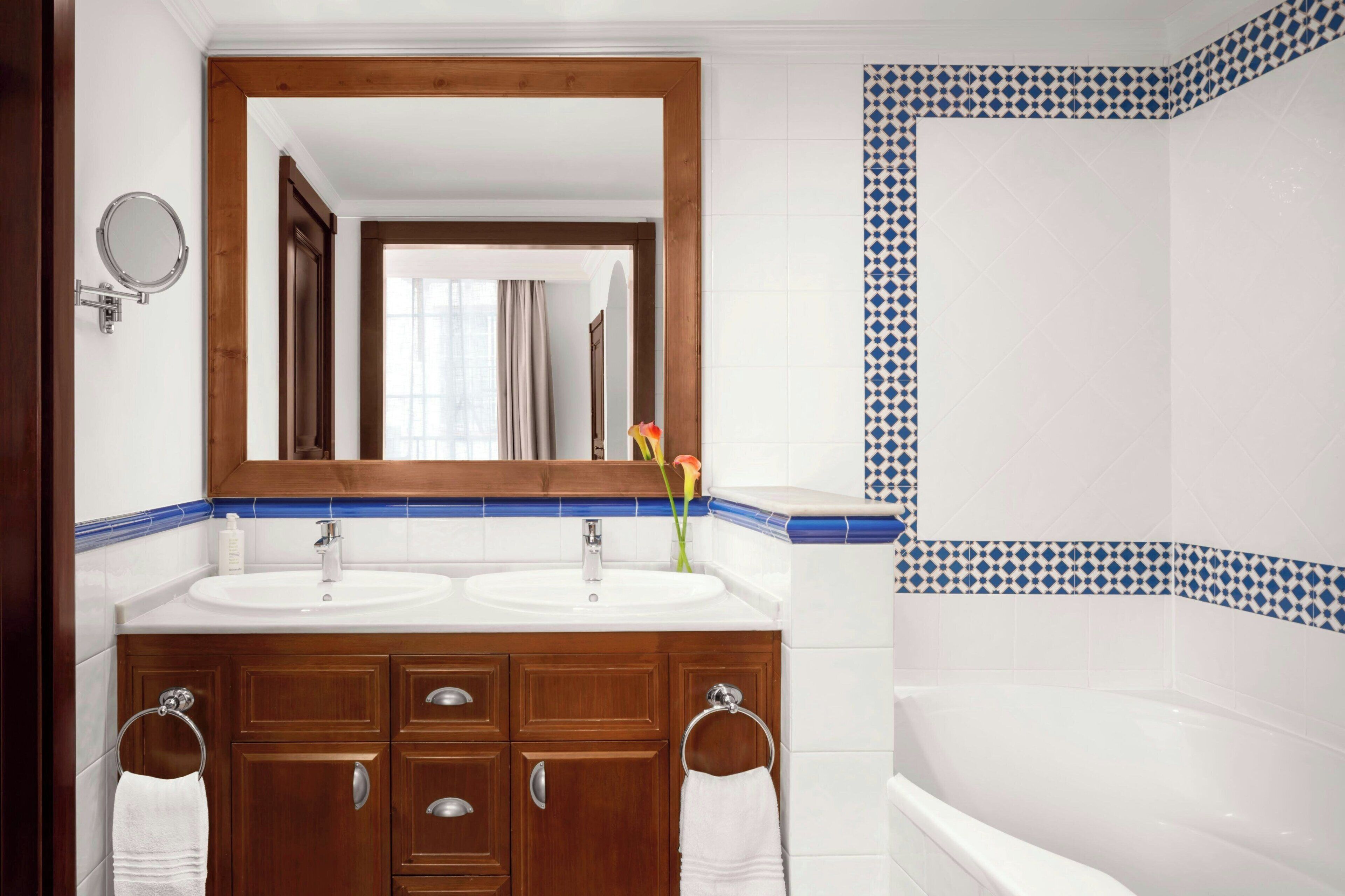 Un baño con dos lavamanos, un espejo grande y una bañera.