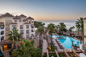 Un resort con piscina, palmeras y vista al océano.