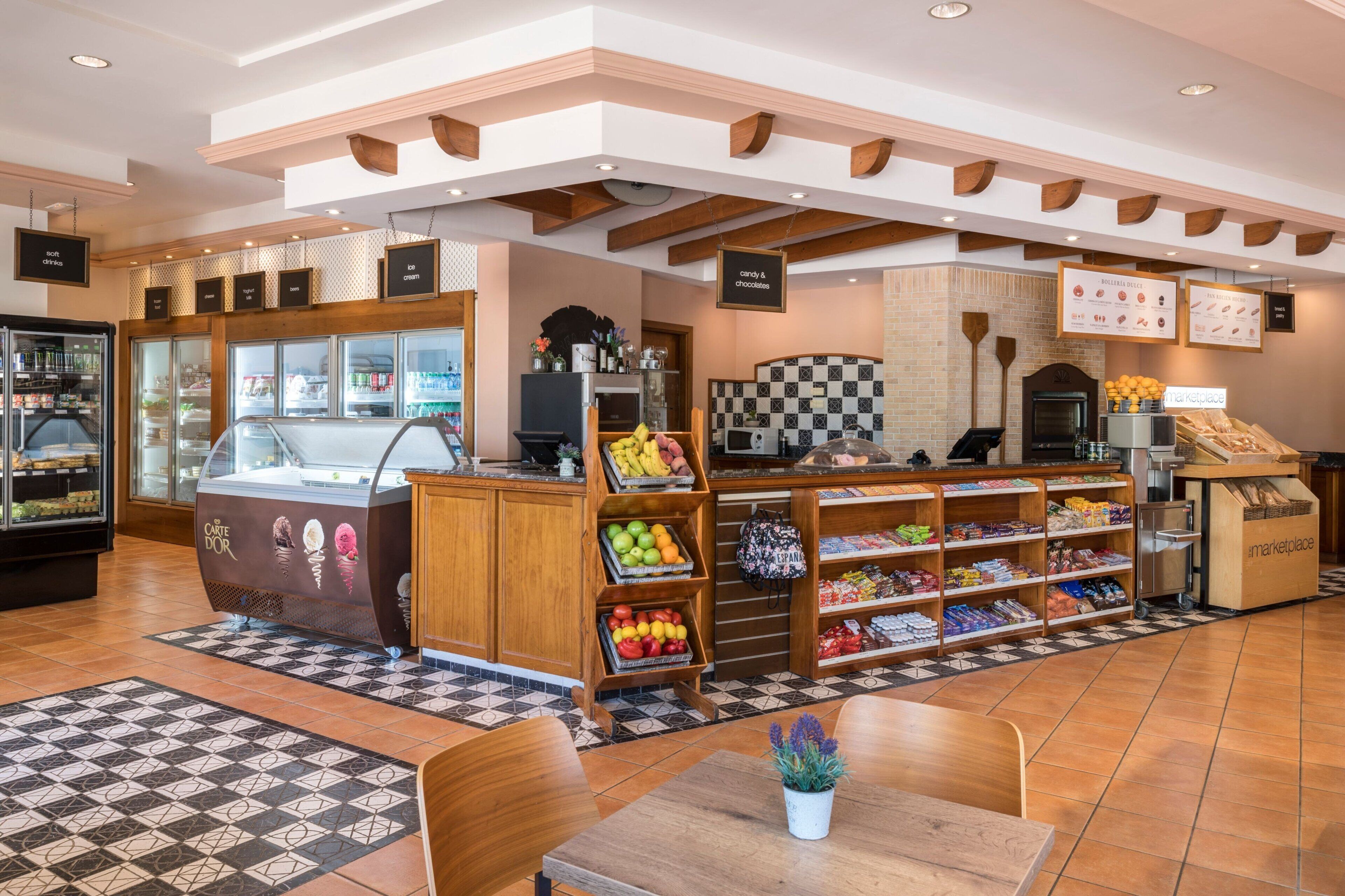 A bakery with a display case, shelves of baked goods, and a seating area with tables.
