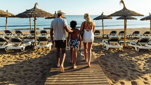 A wooden boardwalk leading to beach chairs and umbrellas on a sandy beach. - Marriott's Playa Andaluza (Estepona)