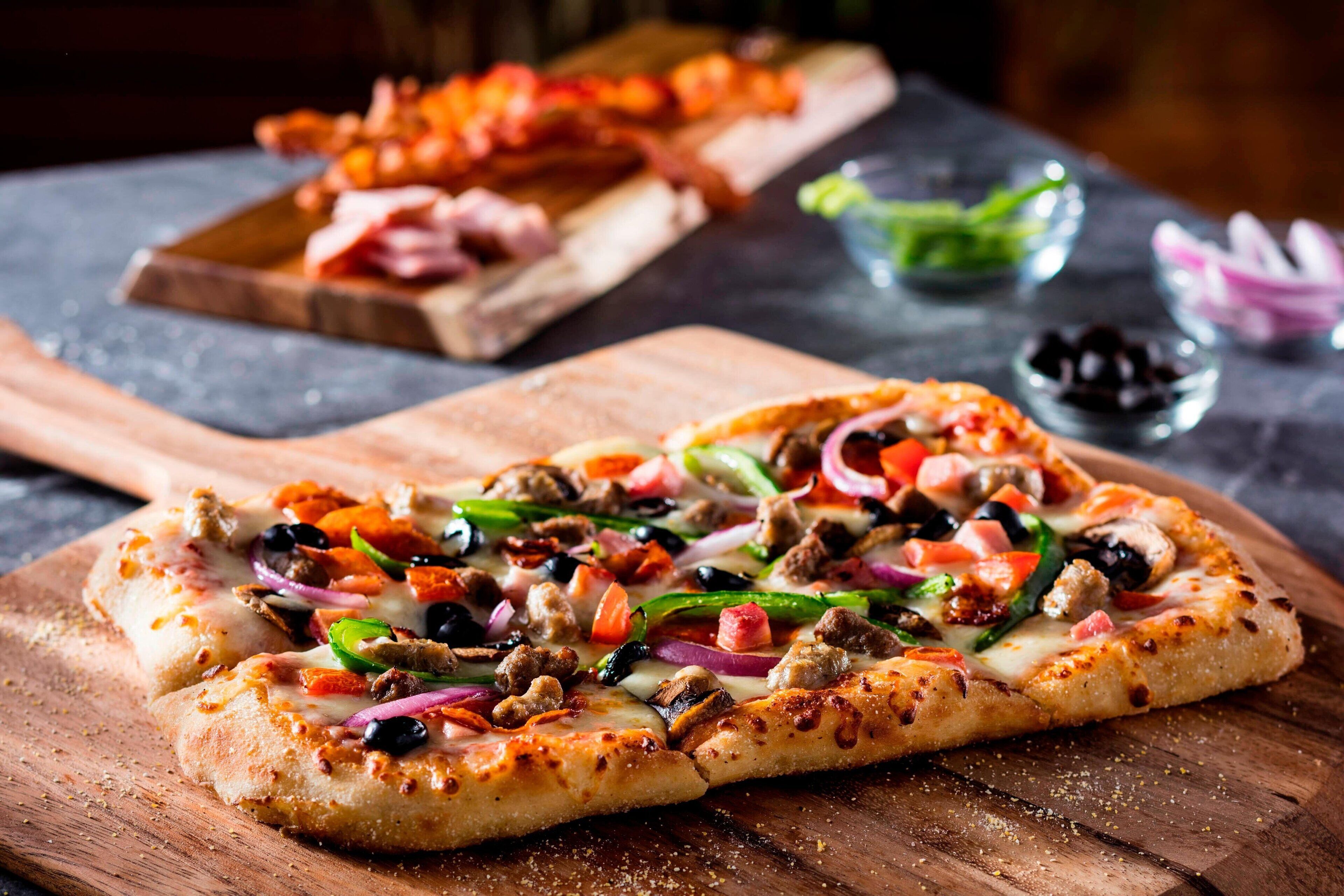 A pizza with various toppings on a wooden board.
