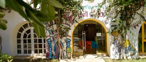 A building entrance with a colorful mural, arched doorways, and a pathway leading to the entrance.